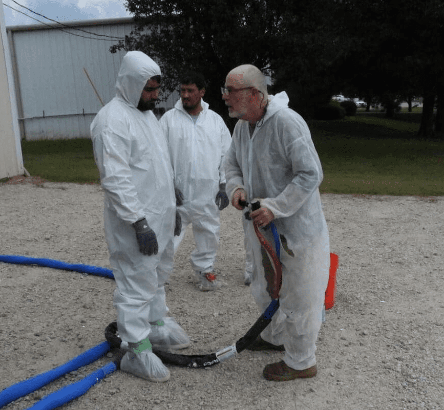 spray foam training instructor demonstrating heated hose handling and tech tips in personal protective wear ppe
